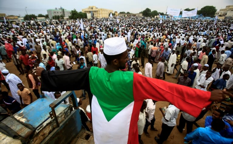 A man dressed in the colours of the Sudanese national flag stands in a crowd gathered to receive President Omar al-Bashir (unseen) during his tour in Nyala, the capital of South Darfur province, on September 21, 2017