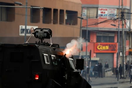 A police officer inside a vehicle aims a weapon during protests after Ecuador's President Lenin Moreno's government ended four-decade-old fuel subsidies in Quito