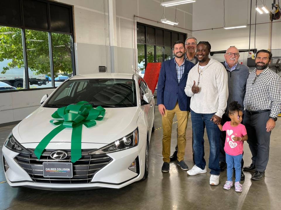 (From left to right) Jacob Gleaton and Bryan Homer from Travelers Insurance, Isaac Taylor, Greg Heppler and Phil Alootti from Caliber Collision, and Genesis, Taylor's daughter, pose with his new car.