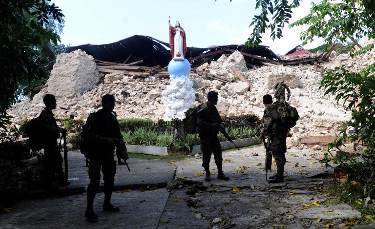 Soldiers stand near the ruins of the historic Holy Cross Parish Church in Maribojoc town in the central Philippine island of Bohol, on October 18, 2013, destroyed by the 7.1 magnitude quake that hit the area on Tuesday