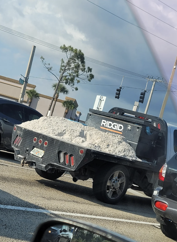 A pickup truck bed overflowing with a pile of materials on a street