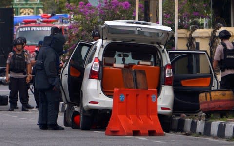 Members of police bomb squad inspect a minivan used in the attack at the regional police headquarters in Pekanbaru, Riau province, Indonesia  - Credit: Akbari/AP