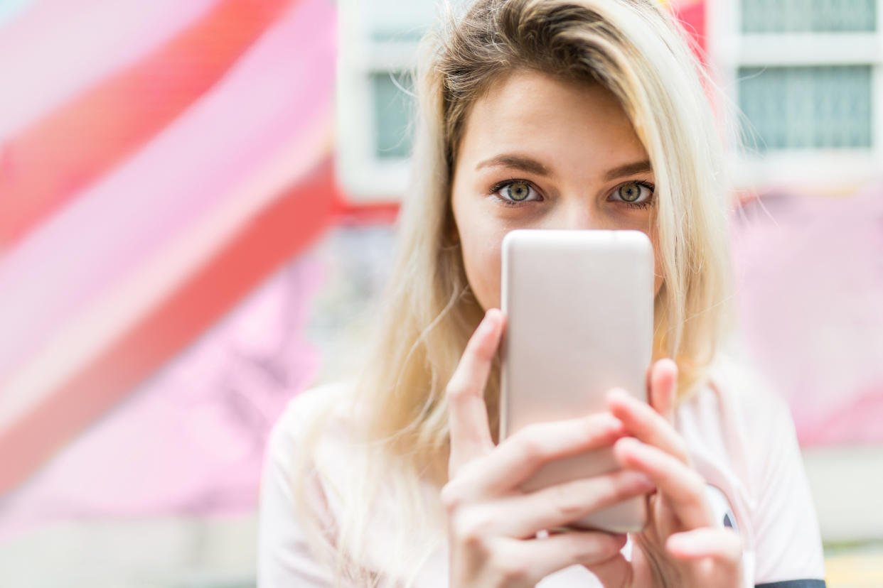 Pictured: Young woman uses Tinder app on her phone. Image: Getty