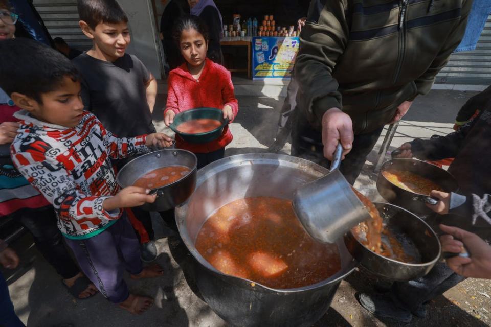 Palestinian children receive cooked food rations as part of a volunteer youth initiative in Rafah in the southern Gaza Strip, on March 5, 2024, amid widespread hunger in the besieged Palestinian territory as the conflict between Israel and the Palestinian militant group Hamas continues.