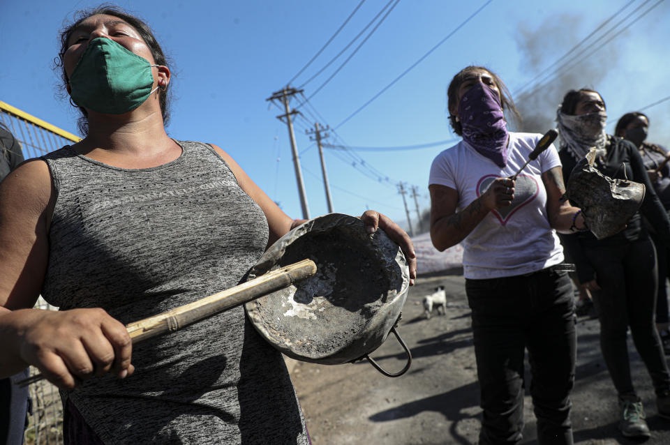 Manifestantes reunidas cerca de una barricada en llamas, durante una protesta pidiendo más ayuda alimentaria del gobierno en la pandemia del coronavirus, en un vecindario de Santiago de Chile, el martes 26 de mayo de 2020. (AP Foto/Esteban Félix)