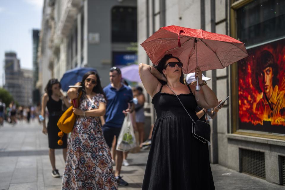 FILE - A woman holds an umbrella to shelter from the sun during a hot sunny day in Madrid, Spain, July 18, 2022. Earth’s fever persisted last year, not quite spiking to a record high but still in the top five or six warmest on record, government agencies reported Thursday, Jan. 12, 2023. (AP Photo/Manu Fernandez, File)