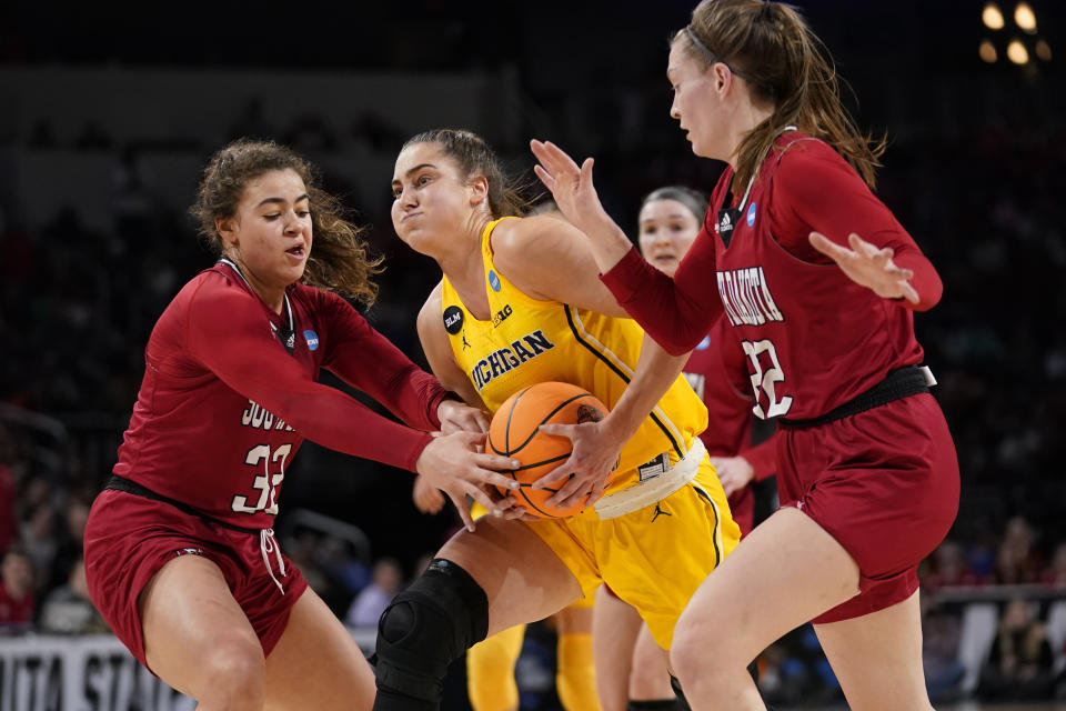 Michigan's Amy Dilk heads to the basket as South Dakota's Kyah Watson (32) and Chloe Lamb, right, defend during the second half of a college basketball game in the Sweet 16 round of the NCAA women's tournament Saturday, March 26, 2022, in Wichita, Kan. (AP Photo/Jeff Roberson)