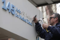 Worker Gabe Ryan removes a sign that includes the name Arthur M. Sackler at an entrance to Tufts School of Medicine, Thursday, Dec. 5, 2019, in Boston. Tufts University says it is stripping the Sackler name from its campus in recognition of the family's connection to the opioid crisis. (AP Photo/Steven Senne)