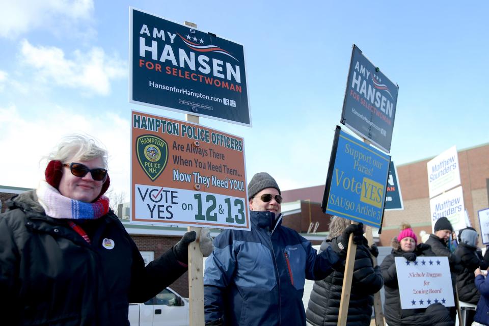 Hampton residents stand outside of Winnacunnet High School campaigning for candidates on Tuesday, March 8, 2022. 