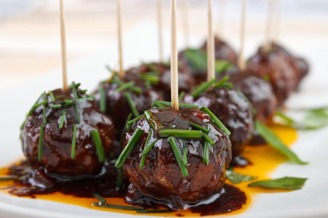 Cocktail meatball snacks with dark barbecue sauce on dish