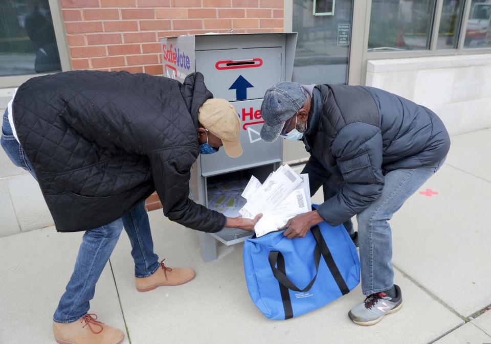 City of Milwaukee employees, Steven Coleman, left, and Larry Ponder remove ballots from a ballot drop box on the sidewalk outside the Washington Park Library on in Milwaukee October 3, 2020.