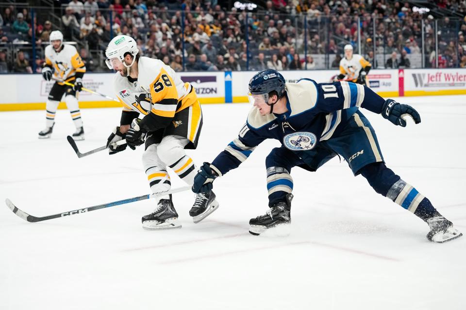 Mar 30, 2024; Columbus, Ohio, USA; Columbus Blue Jackets left wing Dmitri Voronkov (10) reaches past Pittsburgh Penguins defenseman Kris Letang (58) during the third period of the NHL hockey game at Nationwide Arena. The Blue Jackets won 4-3 in a shootout.