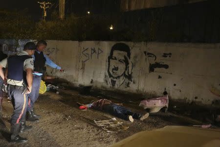 Police officers stand near the body of Anzoategui state policeman Mario Figueroa after he was shot dead in Barcelona, in the state of Anzoategui January 24, 2015. REUTERS/Stringer