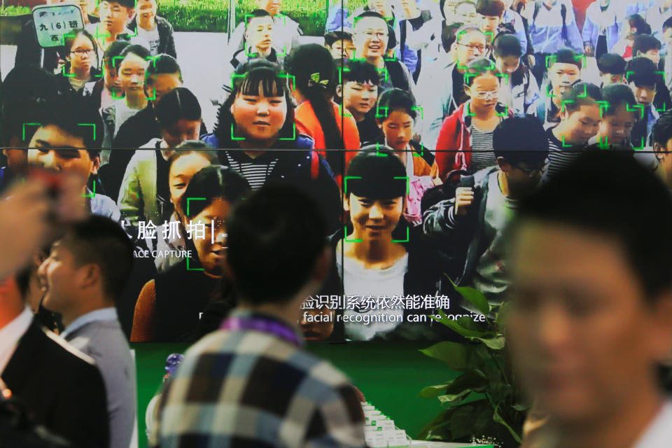 FILE PHOTO; Visitors walk past a screen showing a demonstration of facial recognition software at the Security China 2018 exhibition on public safety and security in Beijing, China October 23, 2018. Picture taken October 23, 2018. REUTERS/Thomas Peter