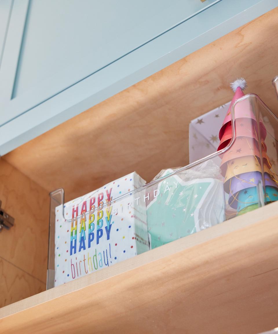 birthday supplies in a storage box in a high kitchen cabinet