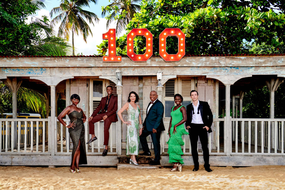 The cast of Death In Paradise pose in eveningwear outside of DI Neville Parker's beach hut, which has the number 