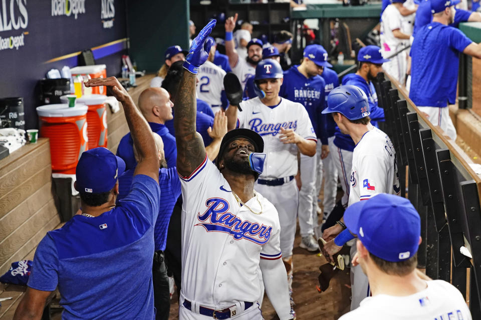 Texas Rangers' Adolis Garcia celebrates in the dugout after hitting a three-run home against the Houston Astros during the sixth inning in Game 5 of the baseball American League Championship Series Friday, Oct. 20, 2023, in Arlington, Texas. (AP Photo/Godofredo A. Vásquez)