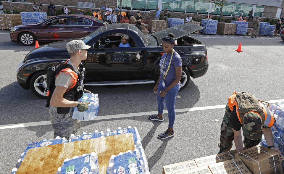 FILE - In this Sept. 18, 2018, file photo, members of the Civil Air Patrol load cars with MREs, (Meals Ready To Eat) water and tarps at distribution area in Wilmington, N.C. Many in Wilmington woke up Wednesday suddenly very tired. The days-long scavenger hunt for gas and ice was over as stores opened and relief agencies were able to roll into the city. (AP Photo/Chuck Burton, File)