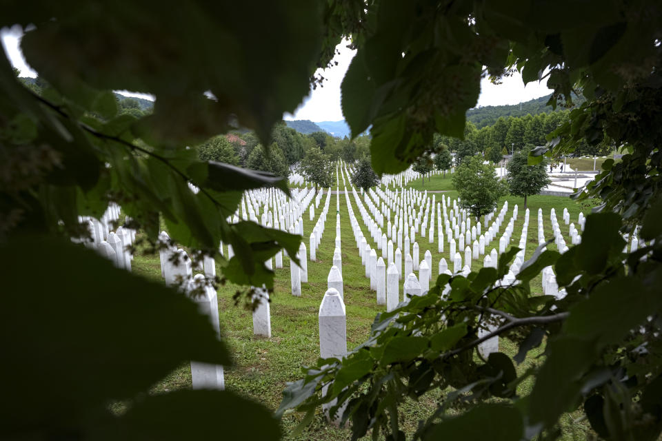 Two people walk in the memorial cemetery in Potocari, near Srebrenica, Bosnia, Tuesday, July 7, 2020. A quarter of a century after they were killed in Sreberenica, eight Bosnian men and boys will be laid to rest Saturday, July 11. Over 8,000 Bosnian Muslims perished in 10 days of slaughter after the town was overrun by Bosnian Serb forces in the closing months of the country’s 1992-95 fratricidal war. (AP Photo/Kemal Softic)