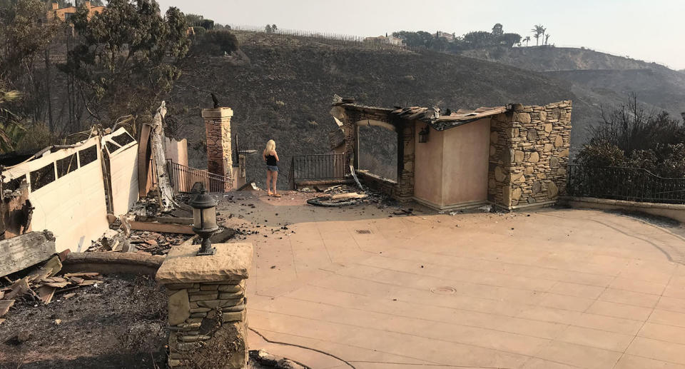 California fires: Tracey Birdsall stands amid the ruins of her Malibu home after it was destroyed by a fire. Source: Supplied