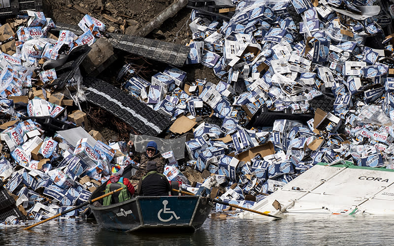 A group of fishermen claim a bottle of beer from a derailed railcar