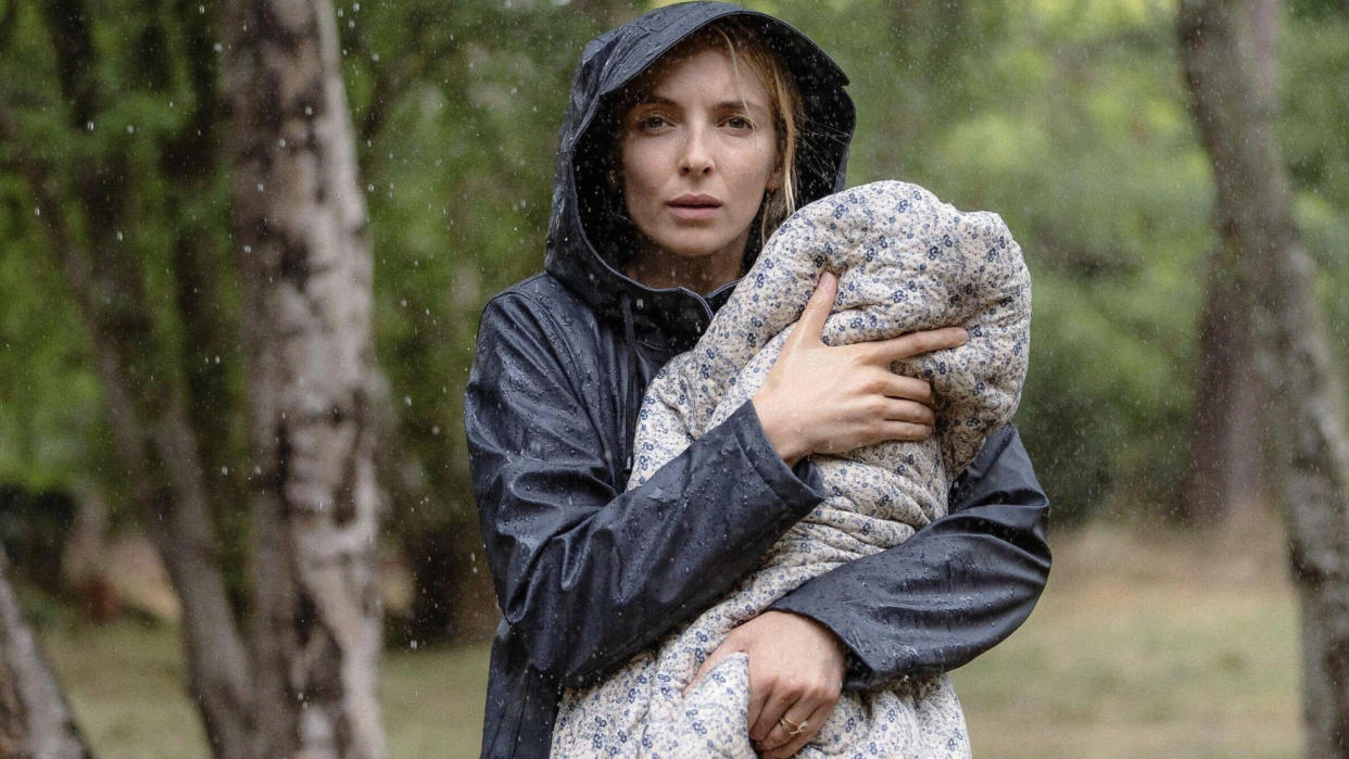  Jodie Comer in the film The End We Start From, holding a baby in the rain. 