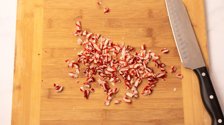 chopped candy canes on wooden board with knife