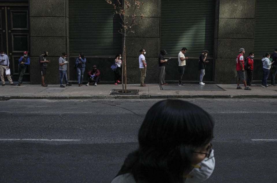People wait in line to collect unemployment insurance, many of them affected by the economic crisis triggered by the spread of the new coronavirus, in downtown Santiago, Chile, Monday, April 6, 2020. (AP Photo/Esteban Felix)