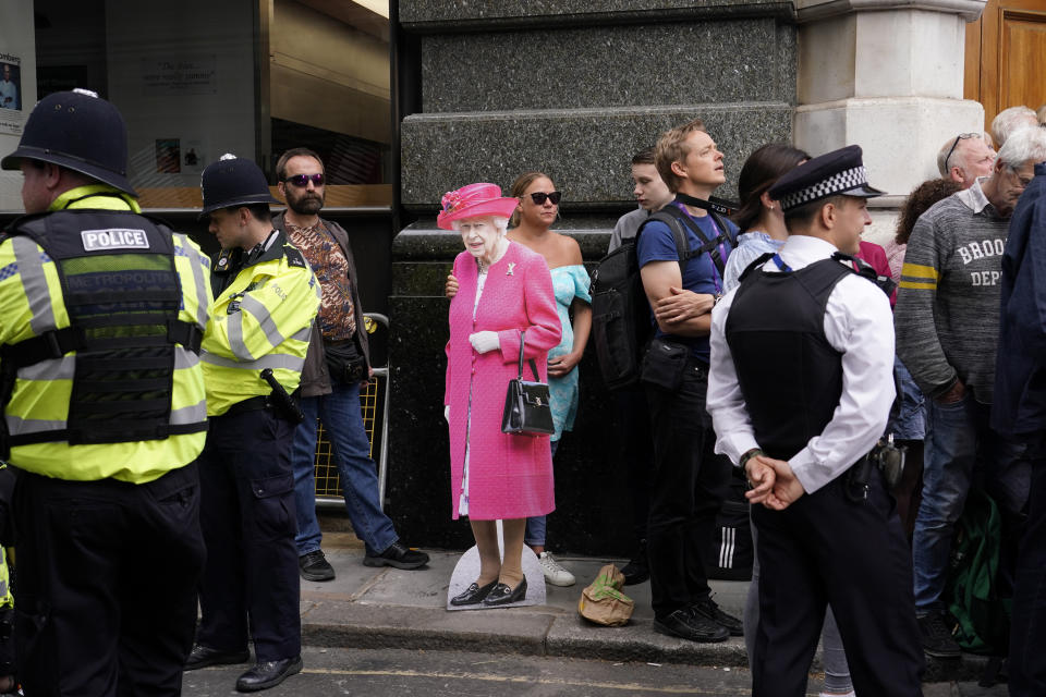 A woman holds a cutout picture of Queen Elizabeth II outside St Paul's Cathedral, while waiting to watch the arrivals for a service of thanksgiving for the reign of Queen Elizabeth II in London, Friday, June 3, 2022 on the second of four days of celebrations to mark the Platinum Jubilee. (AP Photo/Alberto Pezzali)