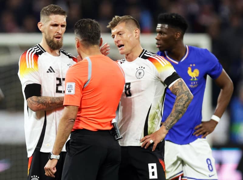 Germany's Robert Andrich (L) and Toni Kroos (2-R) talk with referee Jesus Gil Manzano (2-L) from Spain, during the international friendly soccer match between France and Germany at Groupama Stadium. Andrich from Bundesliga champions Bayer Leverkusen has been nominated into Germany's Euro 2024 squad, with the announcement made by his national team midfield partner Toni Kroos on 15 May. Christian Charisius/dpa