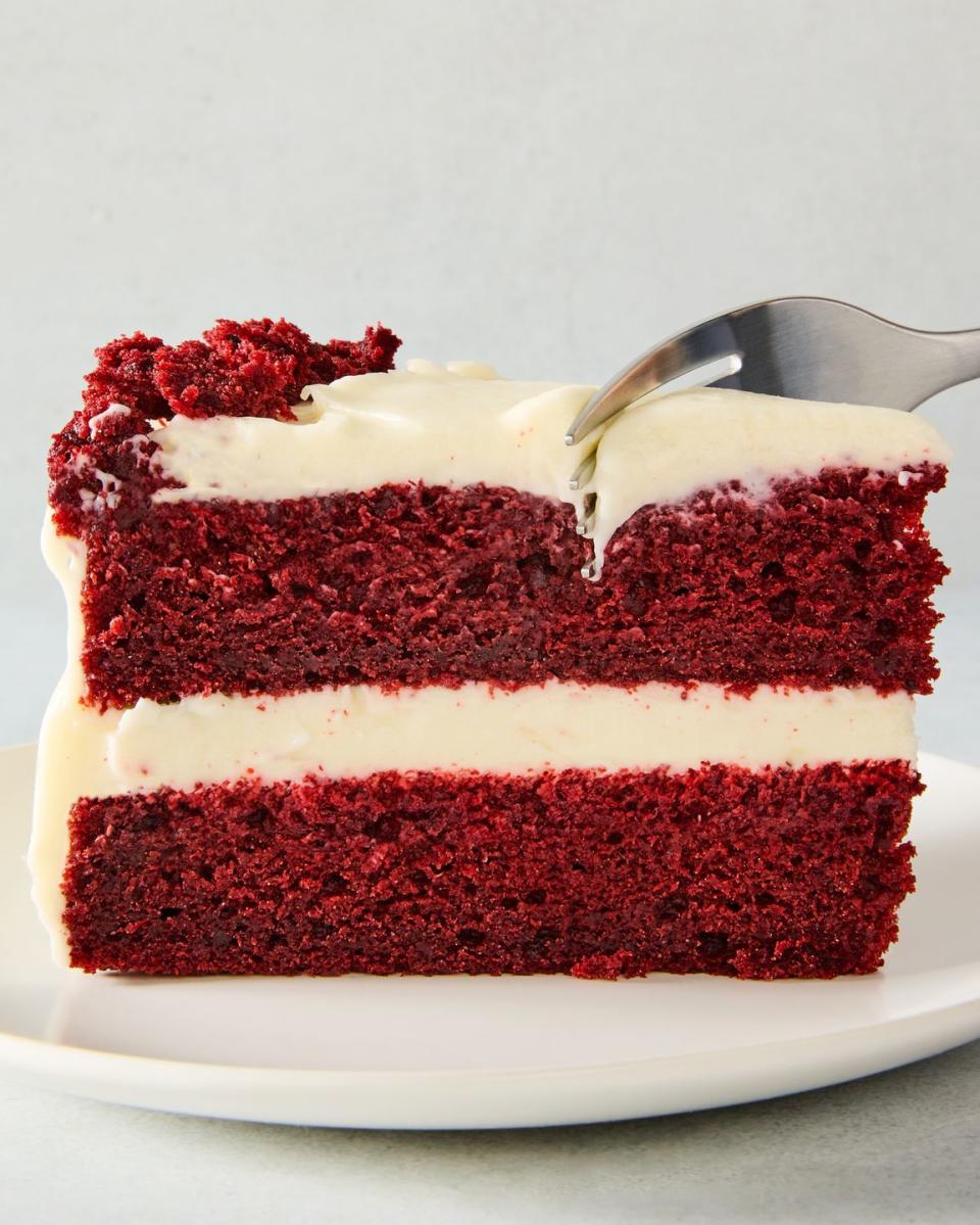 layered red velvet cake with cream cheese icing and pieces of cake