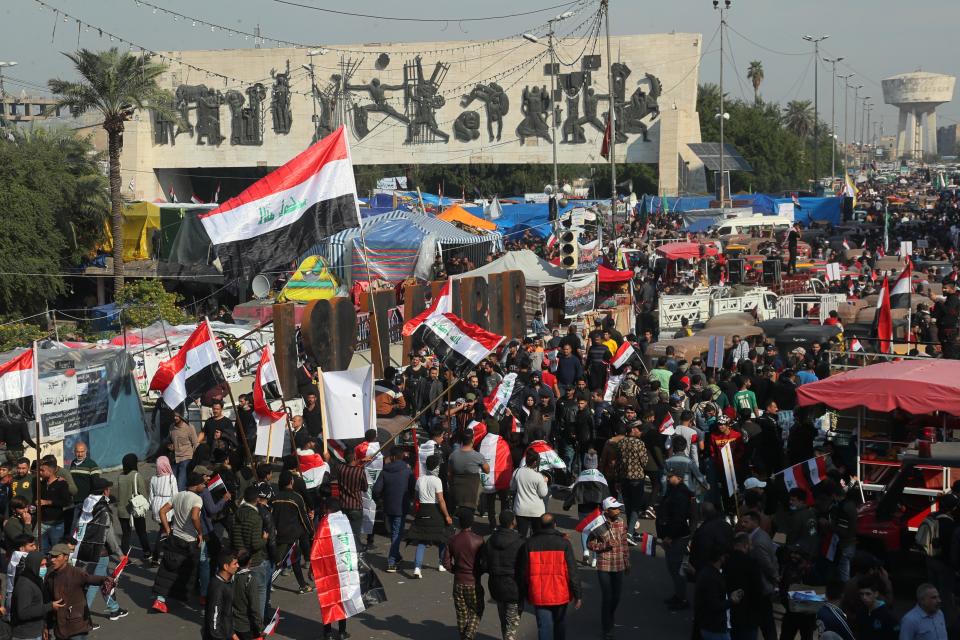 Hundreds of people march inside Tahrir Square carrying national flags and chanting religious slogans in Baghdad, Iraq, Thursday, Dec. 5, 2019. Anti-government protesters say multiple people have suffered stab wounds in Baghdad's Tahrir Square, the epicenter of their movement, after political parties and Iran-backed militia groups briefly joined them, raising fears of infiltration by authorities. (AP Photo/Hadi Mizban)