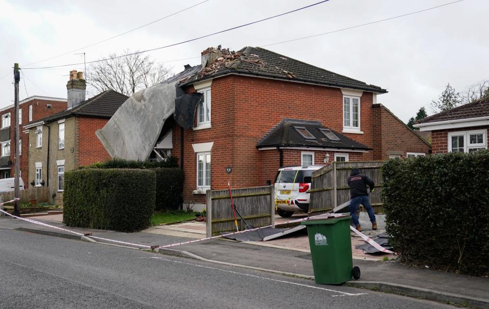 person cleans up a driveway after a roof from a nearby block of flats was blown off in Bitterne, Southampton (PA)