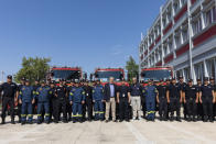 Climate Crisis and Civil Protection Minister Christos Stylianides, center, poses with Romanian and Greek firefighters during a ceremony, in Athens, on Saturday, July 2, 2022. Twenty eight Romanian firefighters, the first of more than 200 firefighters from other European countries that will help their Greek colleagues in fighting wildfires, were welcomed by Climate Crisis and Civil Protection Minister Christos Stylianides and the leadership of Greece's Fire Service. (AP Photo/Yorgos Karahalis)