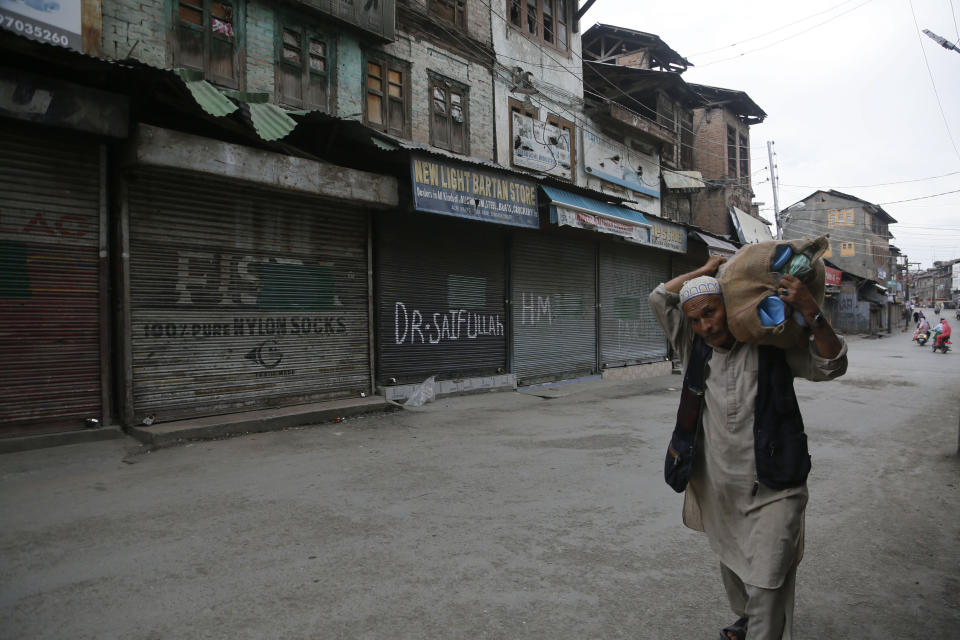 An elderly Kashmiri man selling sandals walks through a closed market in Srinagar, Indian controlled Kashmir, Wednesday, Aug. 28, 2019. India's government, led by the Hindu nationalist Bharatiya Janata Party, imposed a security lockdown and communications blackout in Muslim-majority Kashmir to avoid a violent reaction to the Aug. 5 decision to downgrade the region's autonomy. The restrictions have been eased slowly, with some businesses reopening, some landline phone service restored and some grade schools holding classes again, though student and teacher attendance has been sparse. (AP Photo/Mukhtar Khan)