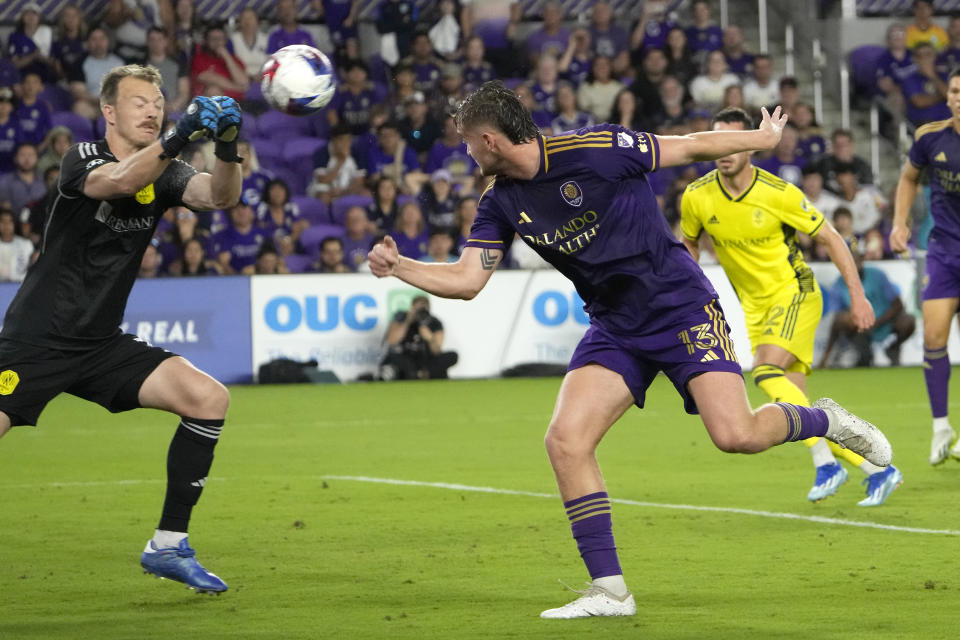 Orlando City forward Duncan McGuire (13) tries get position as Nashville SC goalkeeper Joe Willis, left, blocks a shot during the second half of an MLS playoff soccer match, Monday, Oct. 30, 2023, in Orlando, Fla. (AP Photo/John Raoux)