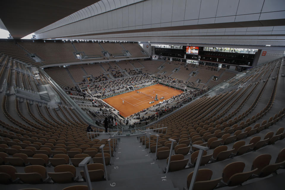 FILE - In this file photo dated Sunday, Oct. 11, 2020, rows of empty seats are seen at centre court at the Roland Garros stadium in Paris as Serbia's Novak Djokovic and Spain's Rafael Nadal warm up for the final match of the French Open tennis tournament. The 2021 French Open schedule is being disrupted by the coronavirus pandemic for the second year in a row, as organizers said Thursday April 8, 2021, the Grand Slam tournament will be delayed by one week because of surging virus cases in France.(AP Photo/Alessandra Tarantino, FILE)