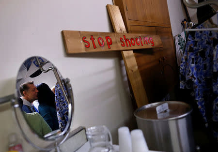 Father Michael Pfleger is reflected in a mirror as he receives a hug from a parishioner as he arrives for the start of his Sunday Service at Saint Sabina Church in Chicago, Illinois, U.S., December 4, 2016. REUTERS/Jim Young