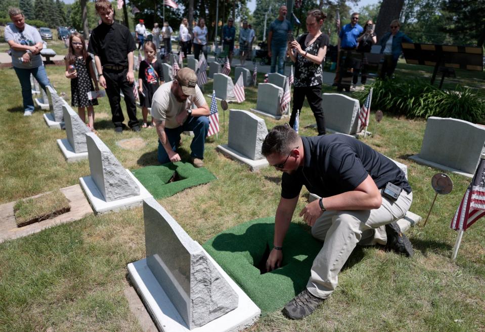 John Van Dyk, left, and Ryan Schnettler add the urns containing their military war dogs Lucky6 and Colt to their final resting places during a memorial service at the Michigan War Dog Memorial in South Lyon on June 17, 2023.