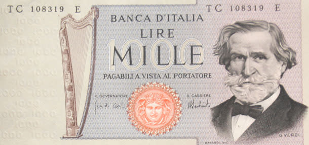 la banconota a cui gli italiani erano più legati prima dell'euro era la mille lire. Un po' per come si presentava, con le immagini dei faccioni di Verdi, Marco Polo o della Montessori stampati sulla carta. Un po' perché era il biglietto più comune. Una cosa è certa:<strong> ci manca</strong> ancora più delle altre.<br><br> La prima cartamoneta da 1.000 lire fu emessa dal Regno di Sardegna tra 1745 e 1746. Lo Stato italiano iniziò a produrle nel 1872. Erano stampate su un'unica faccia, presentavano una cornice con in alto gli stemmi delle città di Genova e Torino e in basso il busto di Colombo. Nel 1894 nacque la prima banconota da 1.000 lire della Banca d'Italia, che però aveva lo stesso disegno e testo della serie della Banca Nazionale, che nel frattempo aveva finito di esistere. La prima 1.000 lire emessa dalla Banca d'Italia fu diffusa nel 1897 e fu disegnata da Rinaldo Barbetti, artista senese. Nel 1932 si aggiunse anche la "Regina del Mare", che al verso presentava tre figure allegorico.<br> La Repubblica Italiana stampò, a partire <strong>dal 1946, otto diverse versioni </strong>di questo tipo di banconota. E' da questo periodo in poi che le mille lire divennero le banconote italiane più popolari. Le prime furono "La Grande M", molto simili ai biglietti stampati durante il Regno d'Italia ma con un diverso contrassegno di Stato. Nel 1947 comparve "l'Italia" ornata di perle, di dimensioni più contenute rispetto alle precedenti. La grafica, assai più moderna, raffigurava sul fronte a sinistra, in una cornice ovale, la testa dell'Italia, ripresa dalle tre grazie della <strong>Primavera di Botticelli</strong>.<br><br> Tra gli anni Sessanta e gli anni Ottanta le mille lire furono incentrate sulla figura di <strong>Giuseppe Verdi (nella foto)</strong>. In una prima versione c'era il ritratto del compositore con decorazioni di ghirlande e bolli colorati. In una seconda opzione, la tecnica per la colorazione dello sfondo migliorò notevolmente; a fianco del ritratto si trovava la celebre Arpa Estense, strumento del 1558 di scuola ferrarese