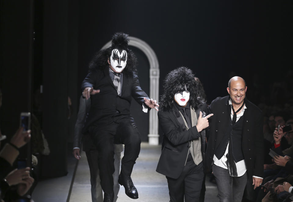 American fashion designer John Varvatos, right, is accompanied by Rock Band Kiss as he acknowledges the applause of the audience, at the end of his men's Autumn-Winter 2014 collection, part of the Milan Fashion Week, unveiled in Milan, Italy, Saturday, Jan. 11, 2014. (AP Photo/Antonio Calanni)