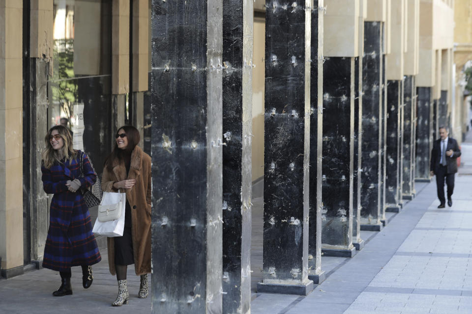 People walk between damaged pillars of Beirut Souks, a 100,000 sq. meters gigantic shopping mall, in Beirut, Lebanon, Friday, Jan. 24, 2020. As cement barricades come up across the capital, blocking the path to major government buildings, Lebanese protesters vowed to continue taking to the street on the 100-day anniversary of the anti-government protests. (AP Photo/Hassan Ammar)