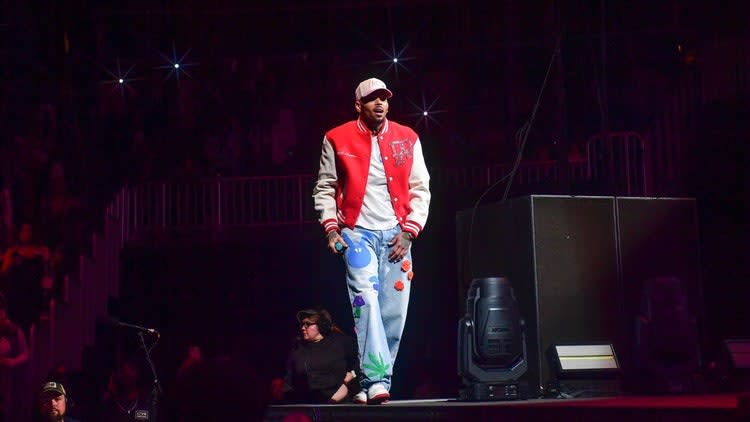 A person wearing a red and white jacket and jeans Description automatically generated