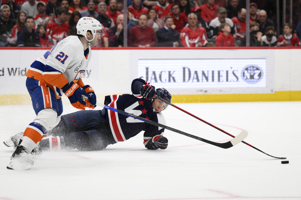 Washington Capitals defenseman Martin Fehervary (42) reaches for the puck against New York Islanders right wing Kyle Palmieri (21) during the first period of an NHL hockey game, Tuesday, April 26, 2022, in Washington. (AP Photo/Nick Wass)