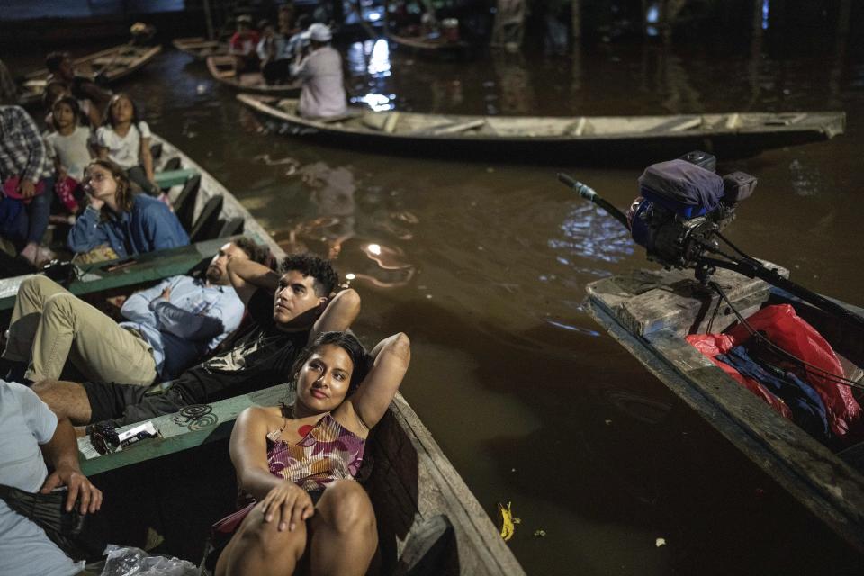 Los espectadores ven desde botes con motor de borda una película proyectada en una pantalla instalada sobre una estructura de madera durante el Festival de Cine Flotante Muyuna, que celebra los bosques tropicales, en el barrio Belén de Iquitos, Perú, el sábado 25 de mayo de 2024. (Foto AP/Rodrigo Abd )