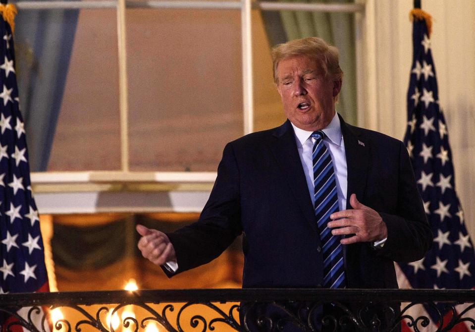 US President Donald Trump gestures from the Truman Balcony upon his return to the White House from Walter Reed Medical Center, where he underwent treatment for Covid-19, in Washington, DC, on October 5, 2020. (Photo by NICHOLAS KAMM / AFP) (Photo by NICHOLAS KAMM/AFP via Getty Images)