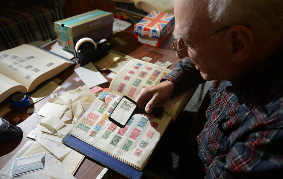 Cape Cod Area Philatelic Group member Peter Bono works his way down a page featuring stamps from the 1920s in one of his albums on a recent Thursday at his home in Yarmouth Port.