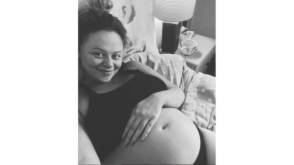 A pregnant Emily Atack in her underwear lying in bed
