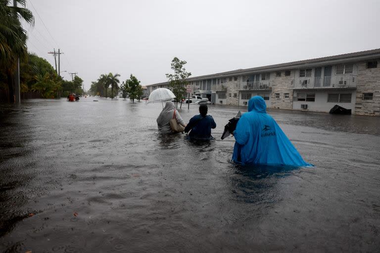  La gente camina por una calle inundada el 12 de junio de 2024, en Hollywood, Florida. Con el paso de la humedad tropical, algunas zonas se han inundado debido a las fuertes lluvias.  