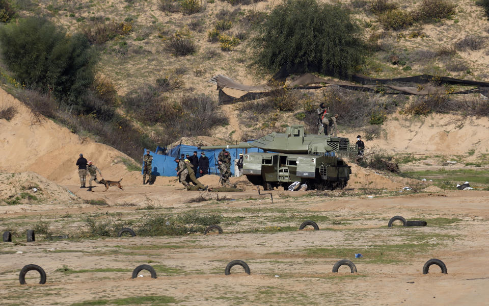 Palestinian militants use a replica of a tank during a military drill organized by military factions outside Gaza City, Tuesday, Dec. 29, 2020. Palestinian militants in the Gaza Strip fired a salvo of rockets into the Mediterranean Sea on Tuesday as part of a self-styled military drill aimed at preparing for a possible war with Israel. (AP Photo/Adel Hana)